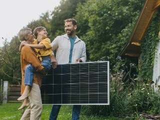 Familie vor Ihrem Eigenheim mit einem Solarpanel.